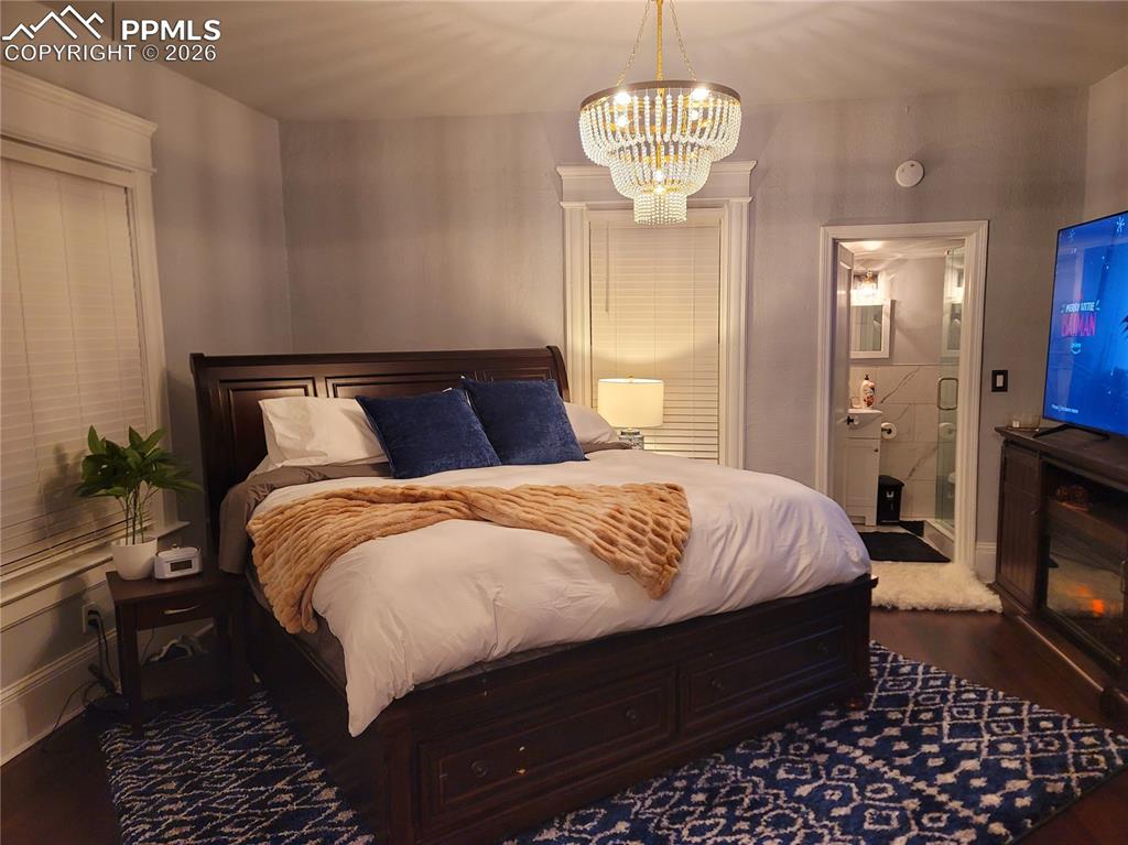 Image 3 of 21: Bedroom featuring dark wood-finish flooring and a decorative tiered chandel
