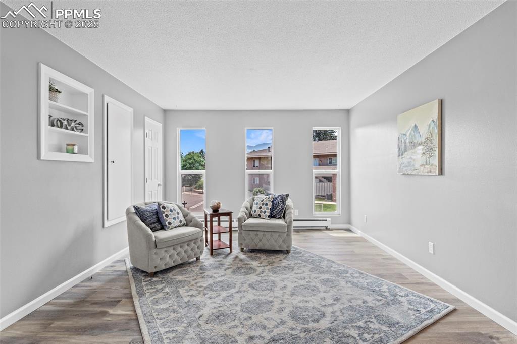 Image 13 of 44: Living area with a textured ceiling, wood finished floors, and a baseboard