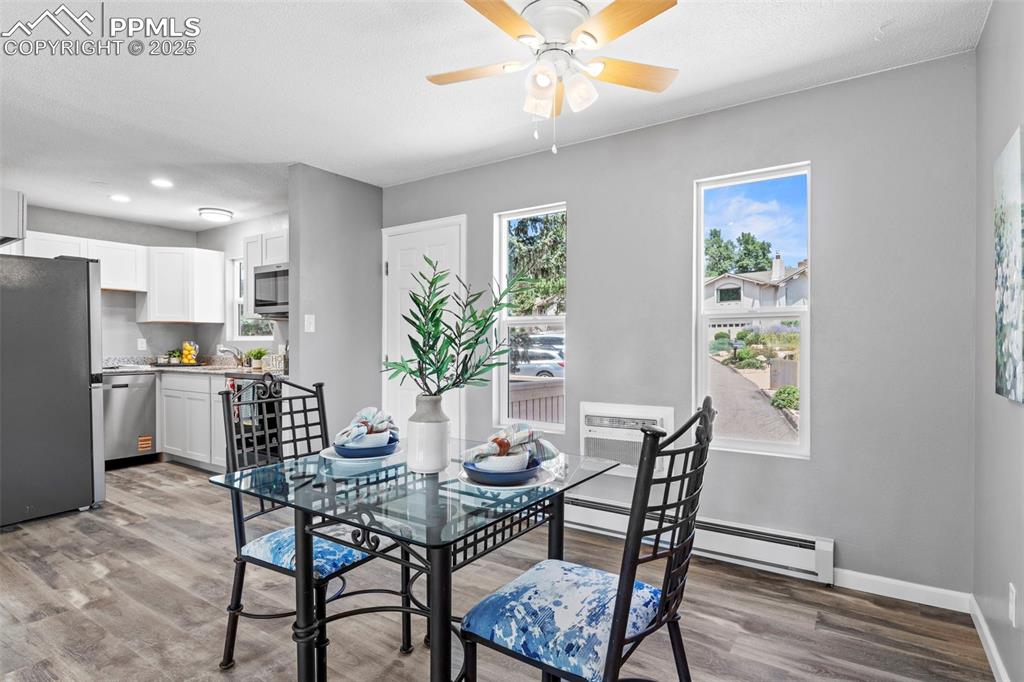 Image 14 of 44: Dining room with light wood-type flooring, a baseboard heating unit, ceilin