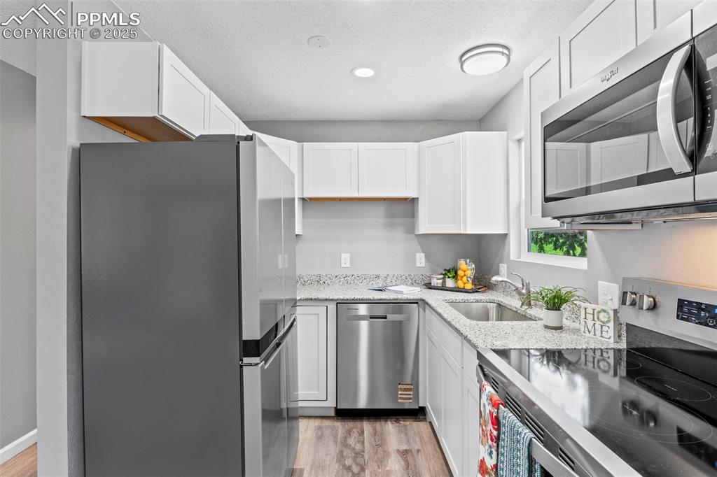Image 16 of 44: Kitchen with stainless steel appliances, a textured ceiling, white cabinetr