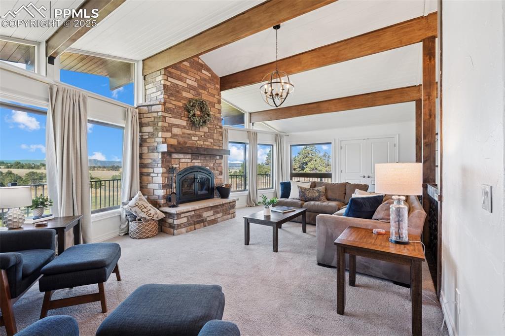 Image 11 of 49: Living room featuring carpet, a wood burning fireplace, and a chandelier