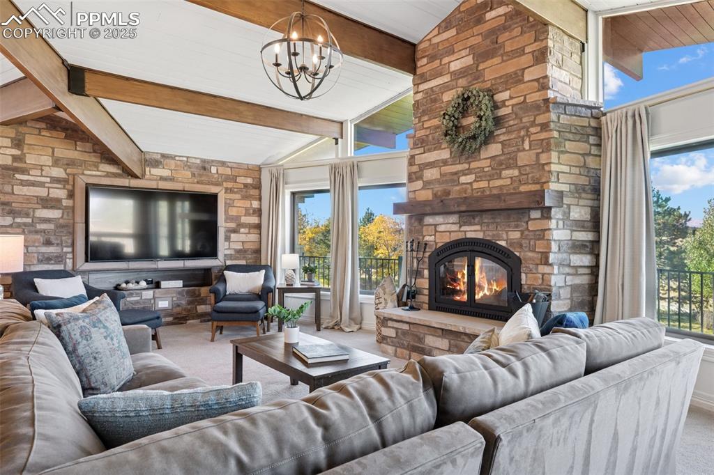 Image 12 of 49: Carpeted living room featuring a large wood burning fireplace and a chandel