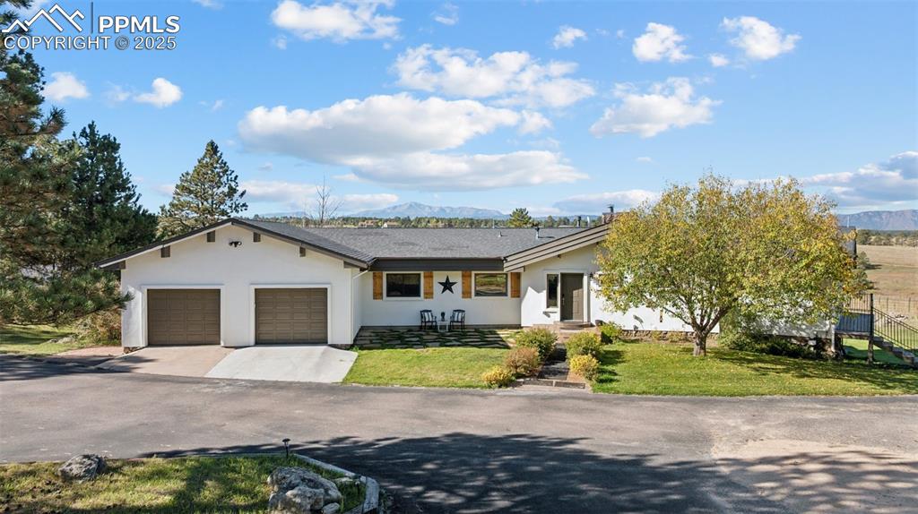 Image 42 of 49: Single story home featuring a mountain view, a front lawn, stucco siding, d