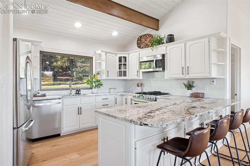 Image 6 of 49: Kitchen featuring open shelves, a peninsula, decorative backsplash, stainle