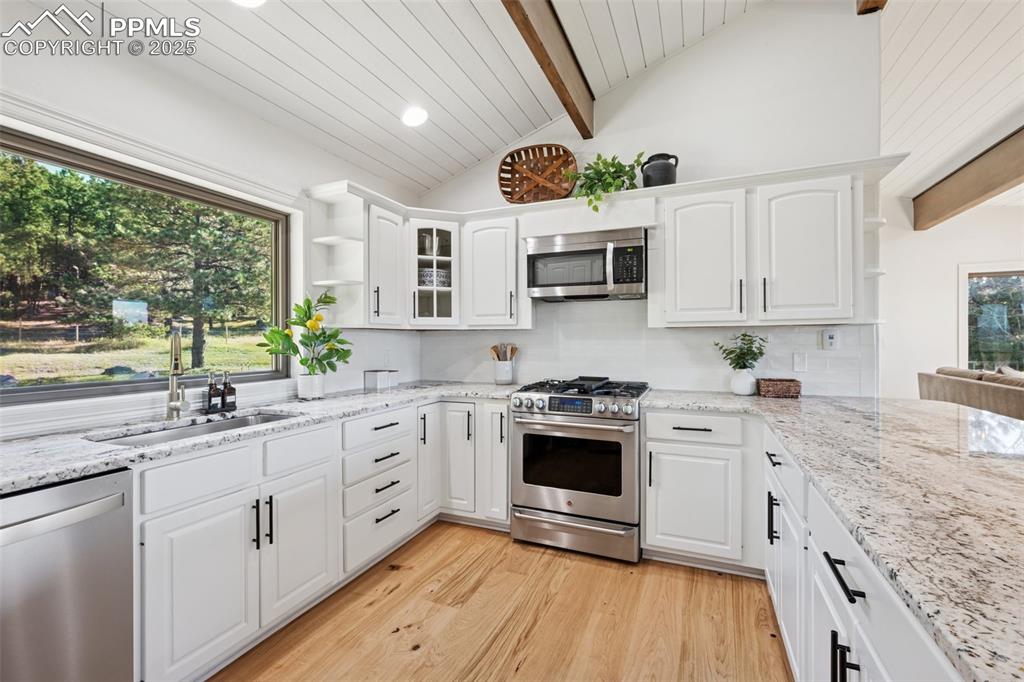 Image 7 of 49: Kitchen with open shelves, stainless steel appliances, light wood finished 