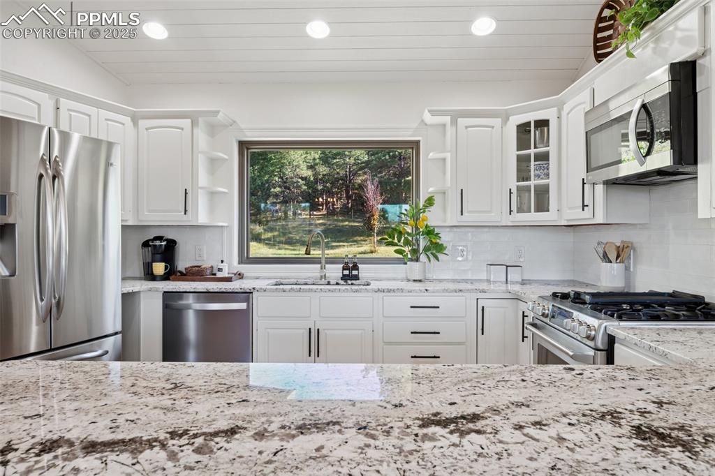 Image 8 of 49: Kitchen featuring open shelves, stainless steel appliances, white cabinets,