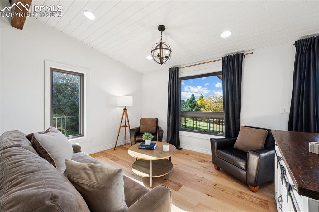 Image 9 of 49: Living area with light wood finished floors, lofted ceiling, recessed light