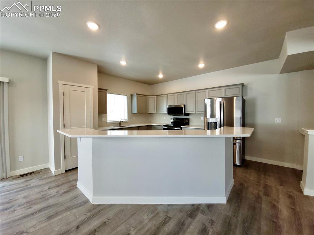 Image 4 of 47: Large kitchen island with quartz countertop and bar height seating availabl