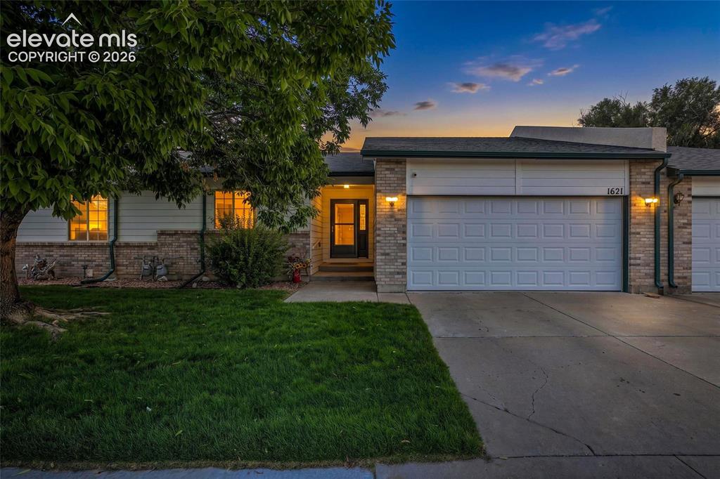Caption: Front exterior featuring a brick and siding facade, an attached garage, a mature tree, and a concret