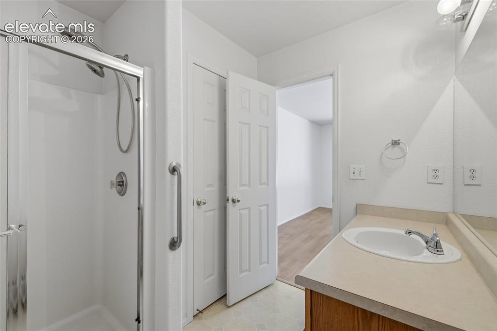 Image 25 of 45: Shower enclosure with a grab bar, wood-finish vanity with an integrated sin