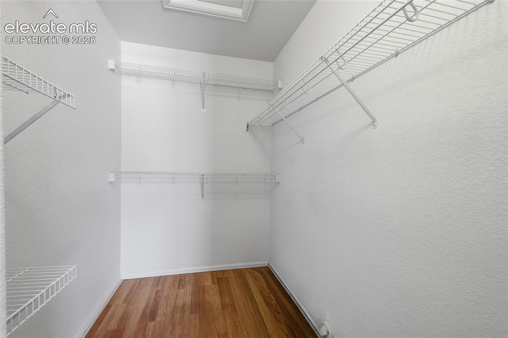 Image 26 of 45: Walk-in closet featuring wire shelving, hanging rods, and wood-finish floor