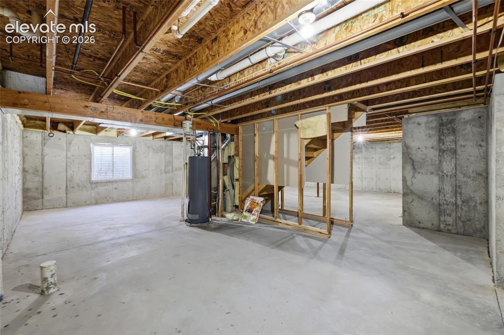 Image 33 of 45: Unfinished basement with concrete flooring, exposed wood beam ceiling, conc