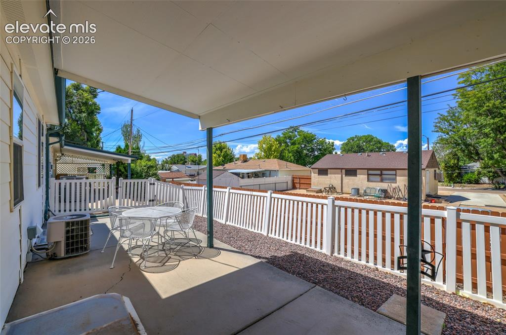 Image 40 of 45: Covered patio with concrete flooring, accented by white picket fencing and