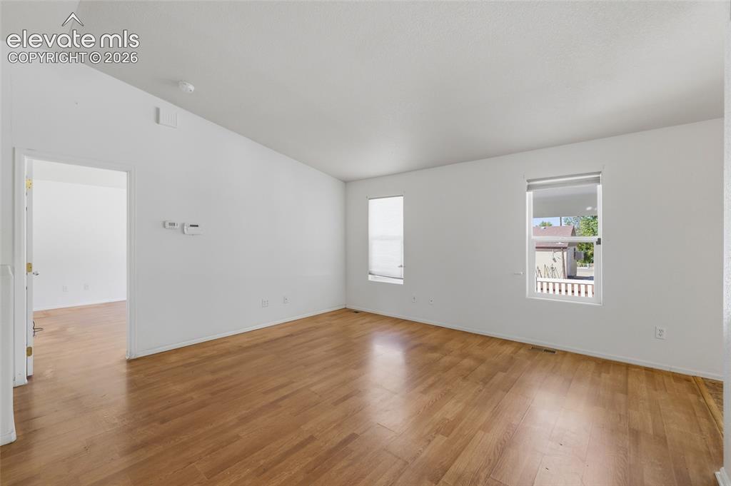Image 9 of 45: Vaulted ceilings, wood-finish flooring, white walls, and multiple windows