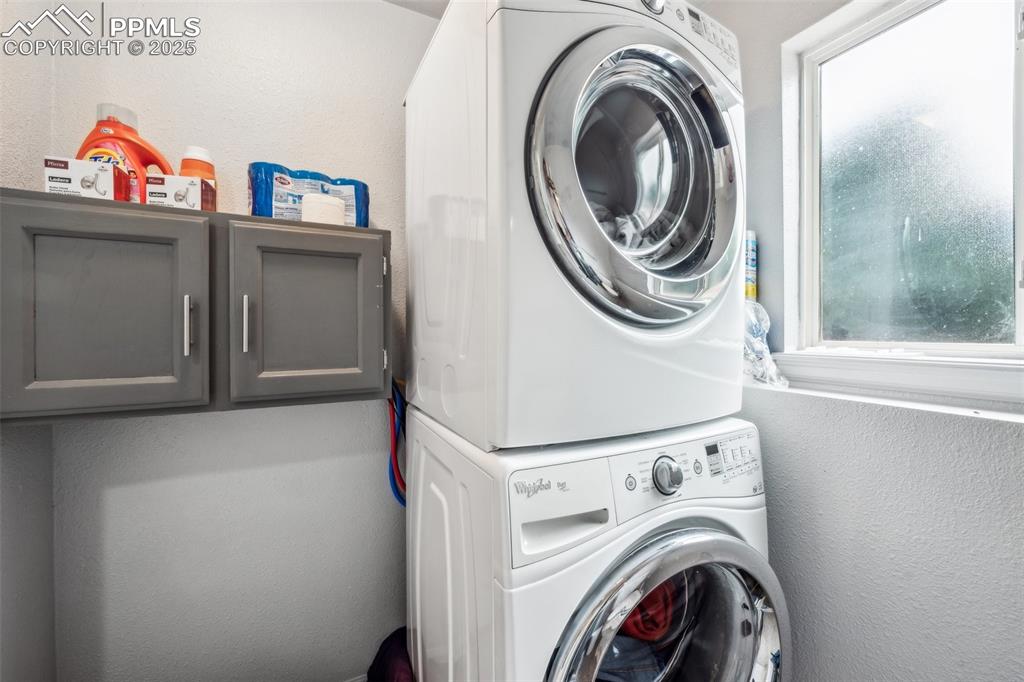 Image 17 of 19: Dedicated laundry area with stacked washer/dryer and storage shelves.