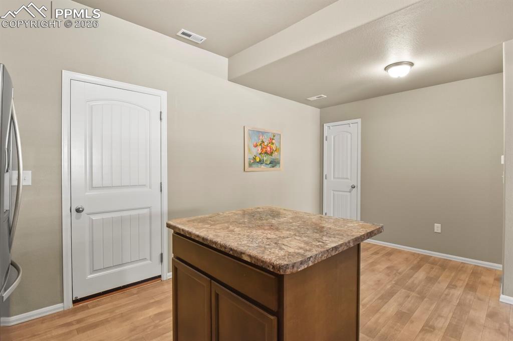 Image 11 of 27: The kitchen features a center island with a speckled countertop, brown cabi