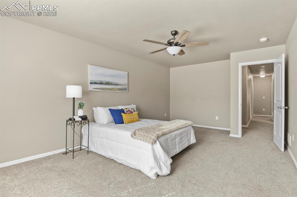 Image 15 of 27: The primary bedroom features neutral-toned walls, plush carpeting, and a ce