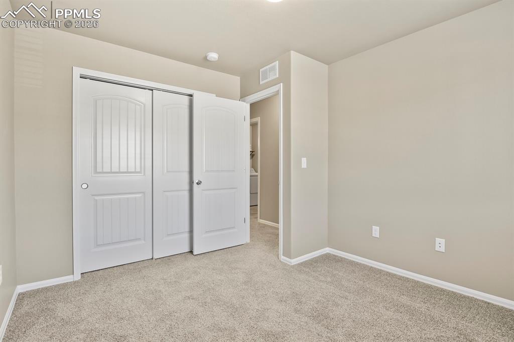 Image 21 of 27: The room features light-colored walls and grey carpet flooring