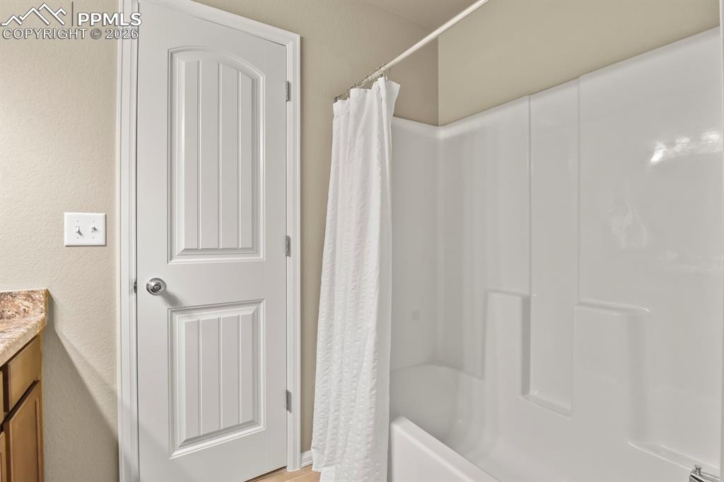 Image 23 of 27: Bathroom featuring a white paneled door, a white shower/tub combination, an