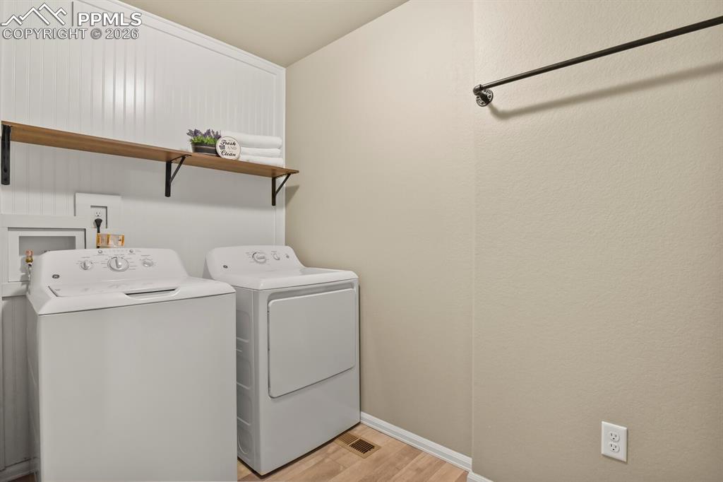 Image 26 of 27: Custom laundry room with wainscoting,  washer, dryer, and an overhead shelf