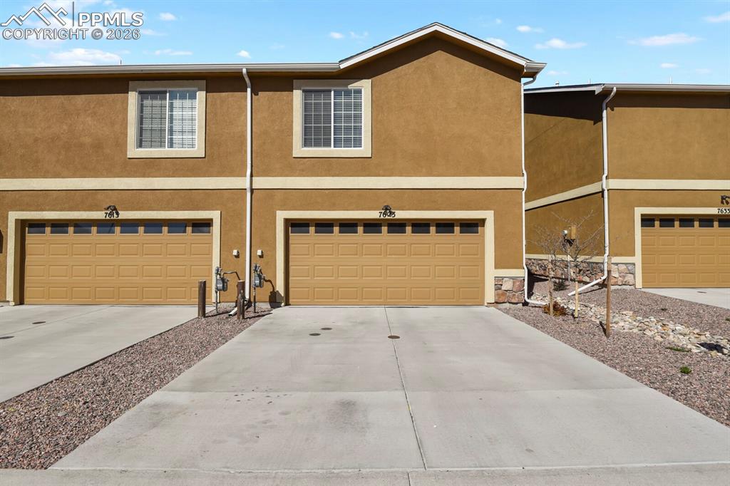 Image 27 of 27: The property features a stucco exterior, attached garages with panel doors,