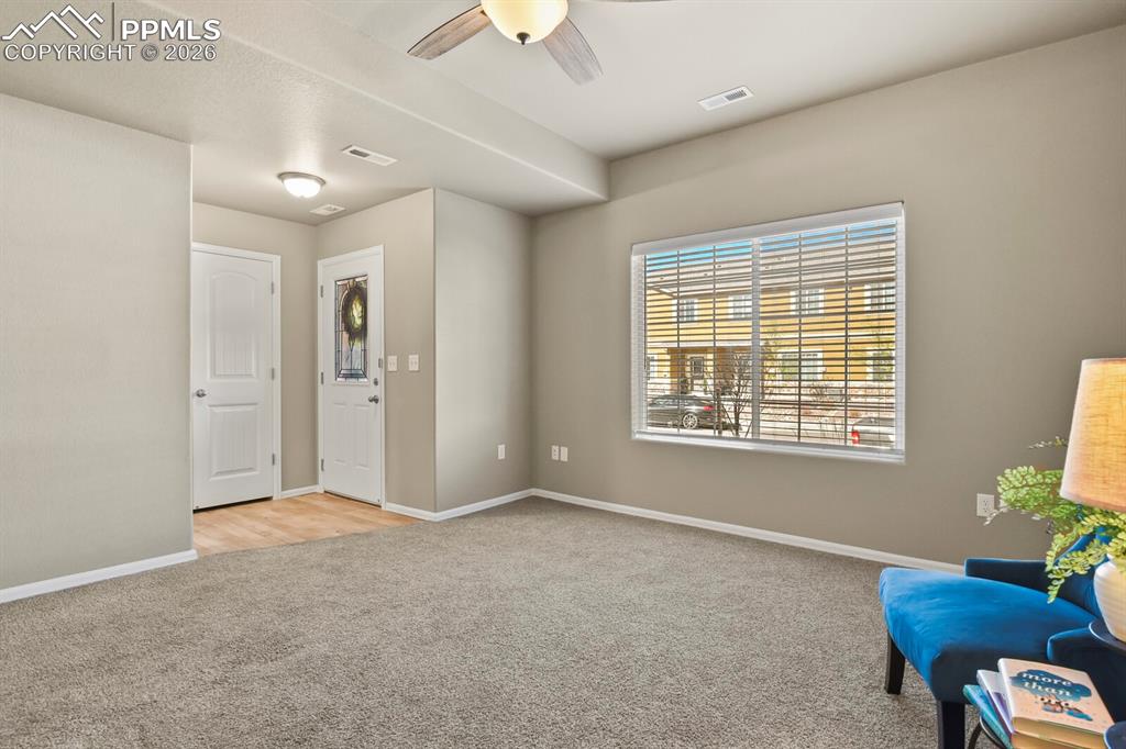 Image 6 of 27: The main living area features neutral-toned walls, plush carpeting, and a c