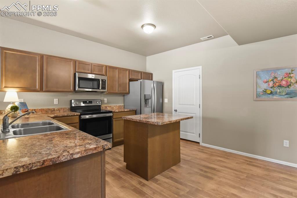Image 8 of 27: The property features a kitchen with wood cabinetry, stainless steel applia