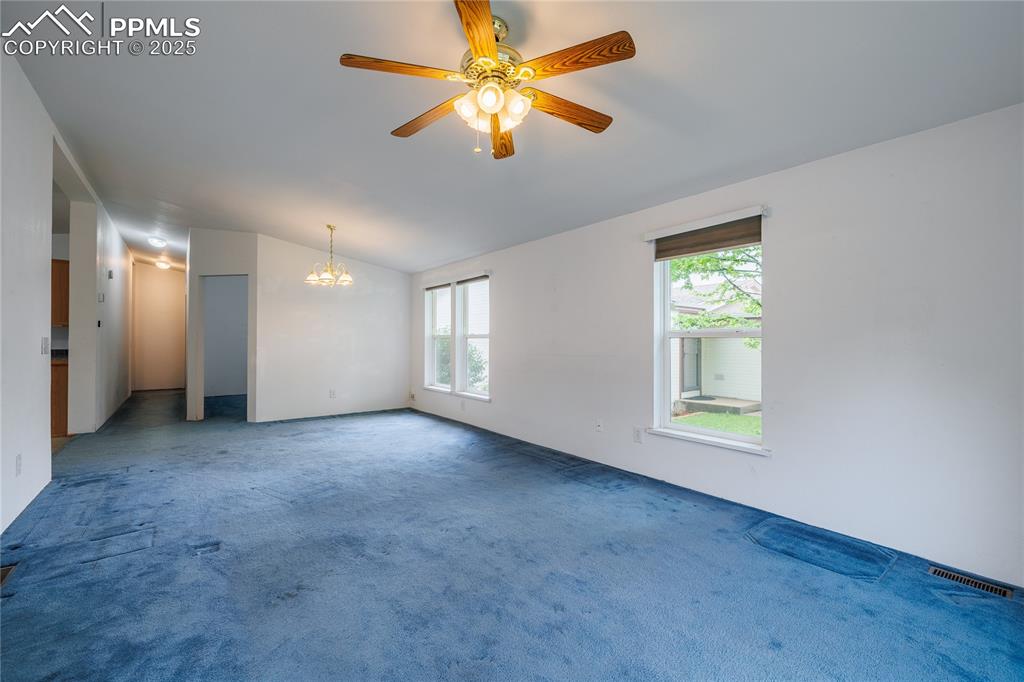 Image 12 of 26: Spare room with vaulted ceiling, plenty of natural light, a chandelier, lig