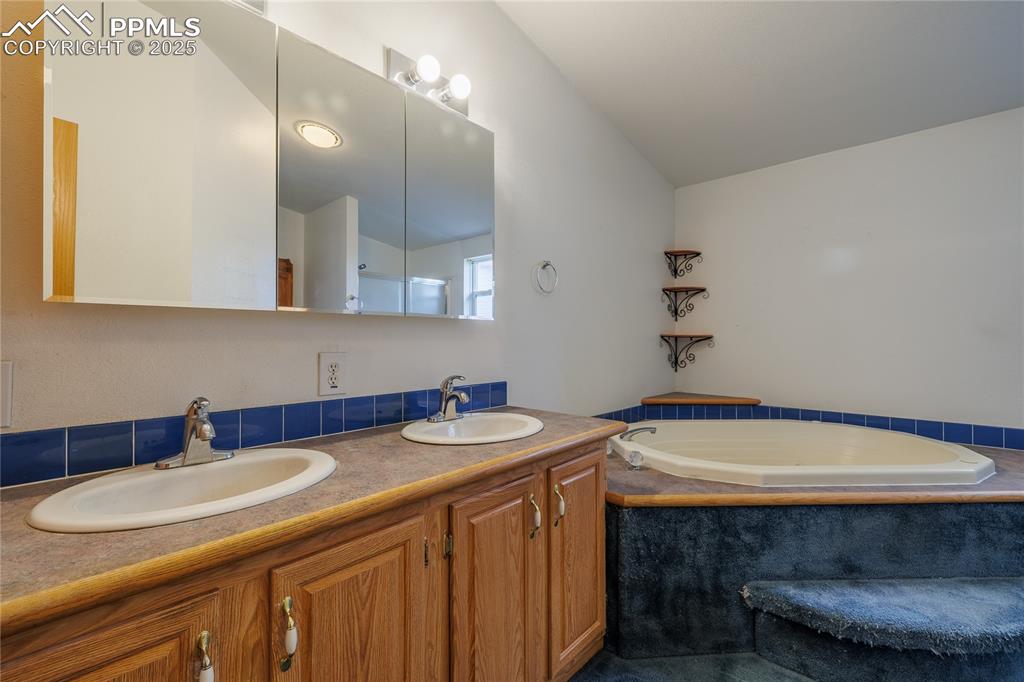 Image 15 of 26: Bathroom with double vanity, a bath, and lofted ceiling