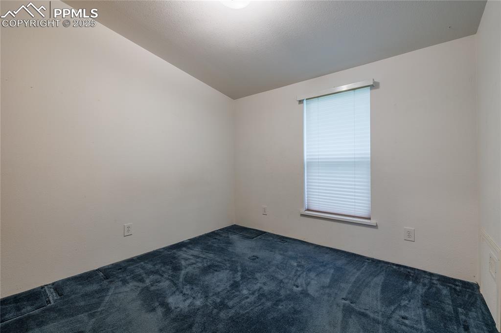 Image 17 of 26: Empty room with carpet floors and lofted ceiling