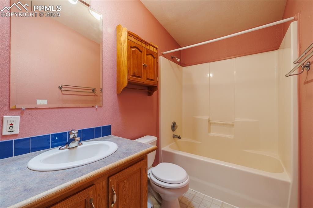 Image 21 of 26: Full bathroom with toilet, vanity, and  shower combination