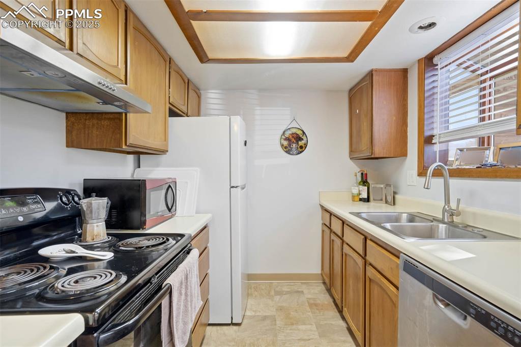 Image 15 of 35: Kitchen with black electric range oven, under cabinet range hood, stainless