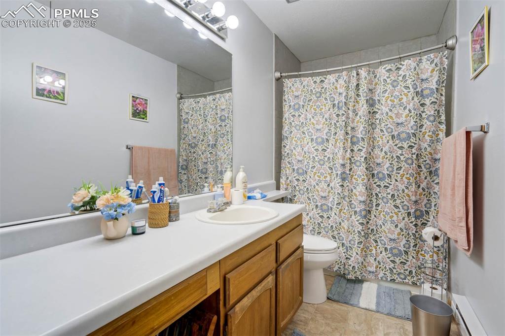 Image 20 of 35: Full bath featuring vanity, a baseboard radiator, a shower with curtain, an
