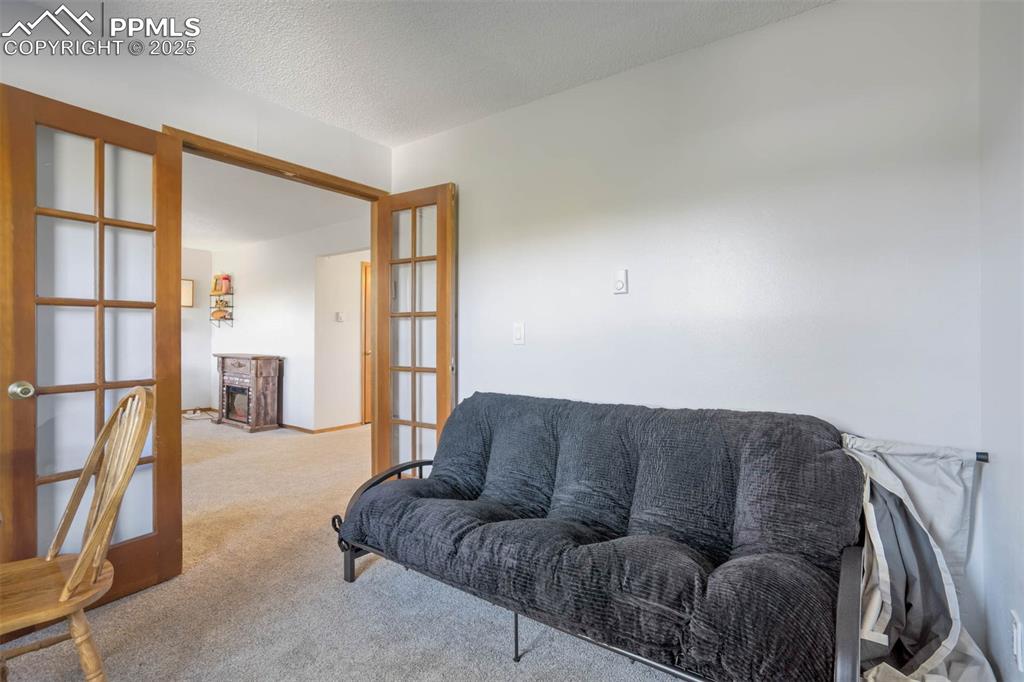 Image 23 of 35: Carpeted living area with a textured ceiling and french doors