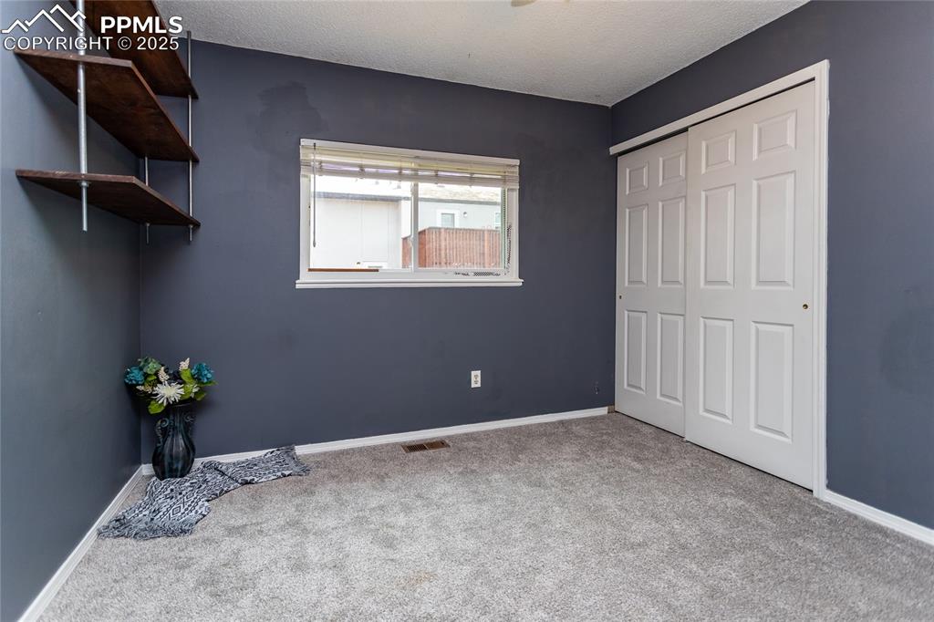 Image 13 of 50: Unfurnished bedroom with carpet flooring, baseboards, a closet, and a textu