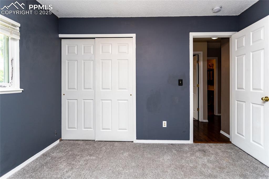 Image 14 of 50: Unfurnished bedroom with carpet, a closet, baseboards, and a textured ceili