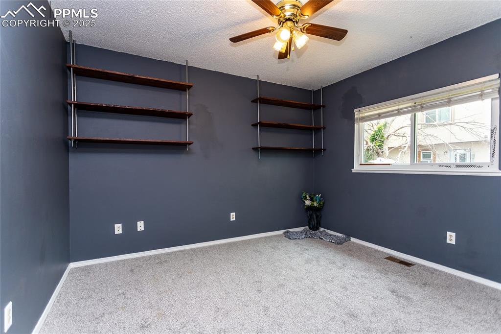 Image 15 of 50: Empty room with carpet, a ceiling fan, a textured ceiling, and baseboards