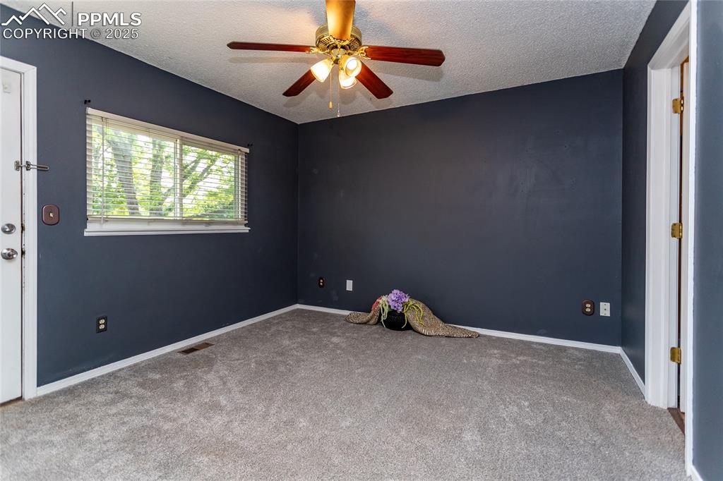 Image 16 of 50: Spare room featuring carpet floors, a ceiling fan, a textured ceiling, and