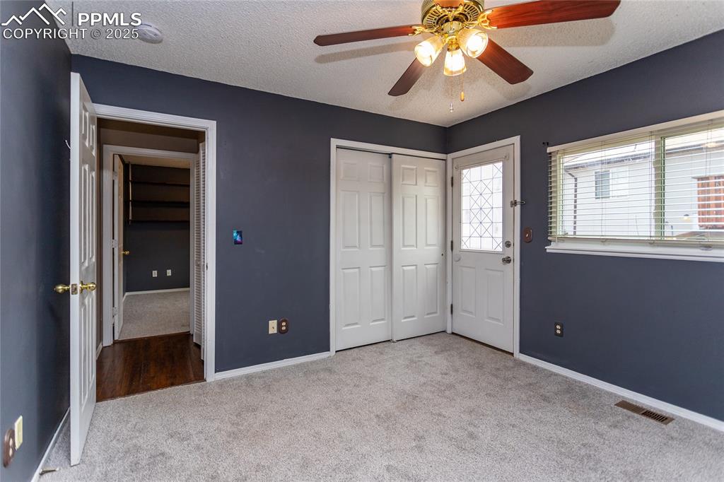 Image 18 of 50: Unfurnished bedroom with carpet, baseboards, a textured ceiling, ceiling fa