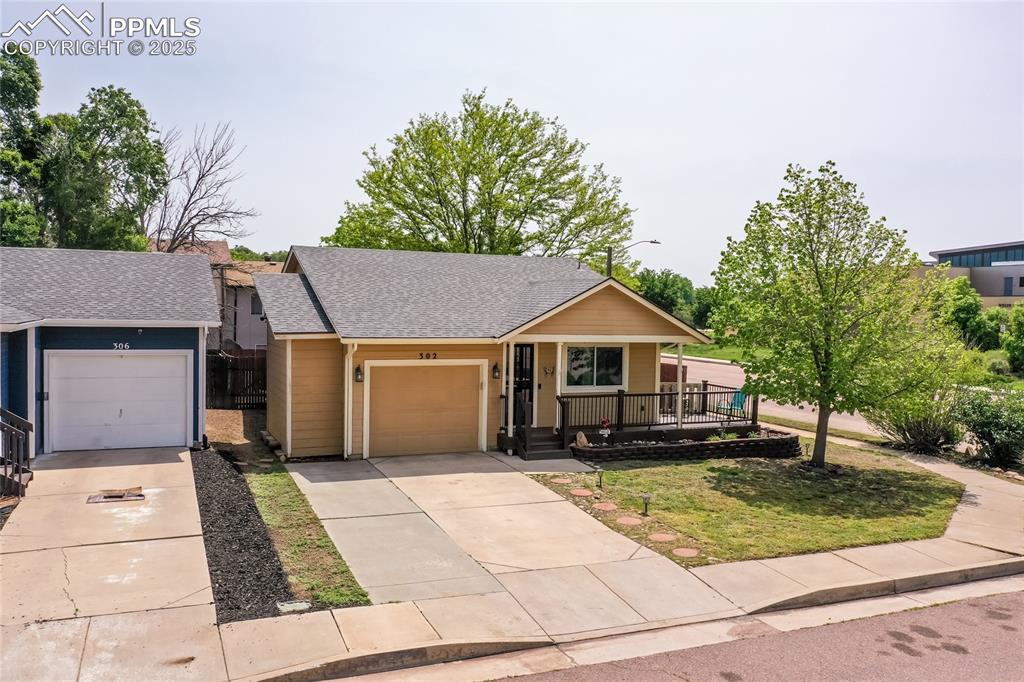 Image 2 of 50: View of front of home with a porch, driveway, a garage, and a shingled roof