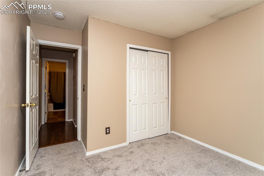 Image 20 of 50: Unfurnished bedroom with a closet, carpet flooring, baseboards, and a textu