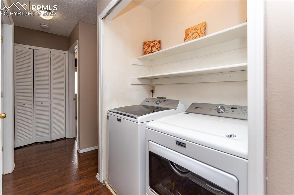 Image 21 of 50: Laundry room with washing machine and dryer, dark wood-style floors, a text