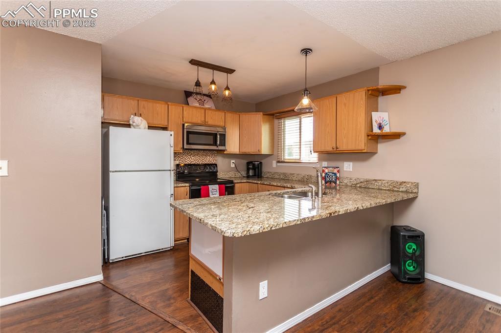 Image 33 of 50: Kitchen featuring stainless steel microwave, freestanding refrigerator, a s