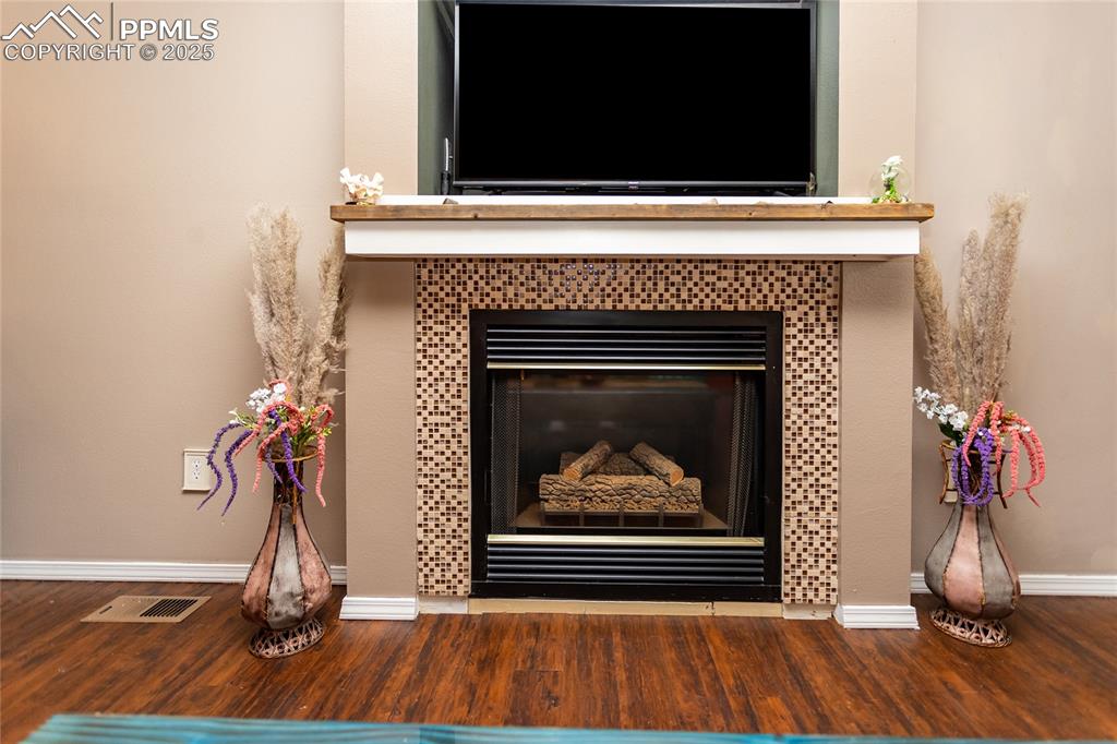Image 39 of 50: Detailed view of a fireplace, baseboards, and wood finished floors
