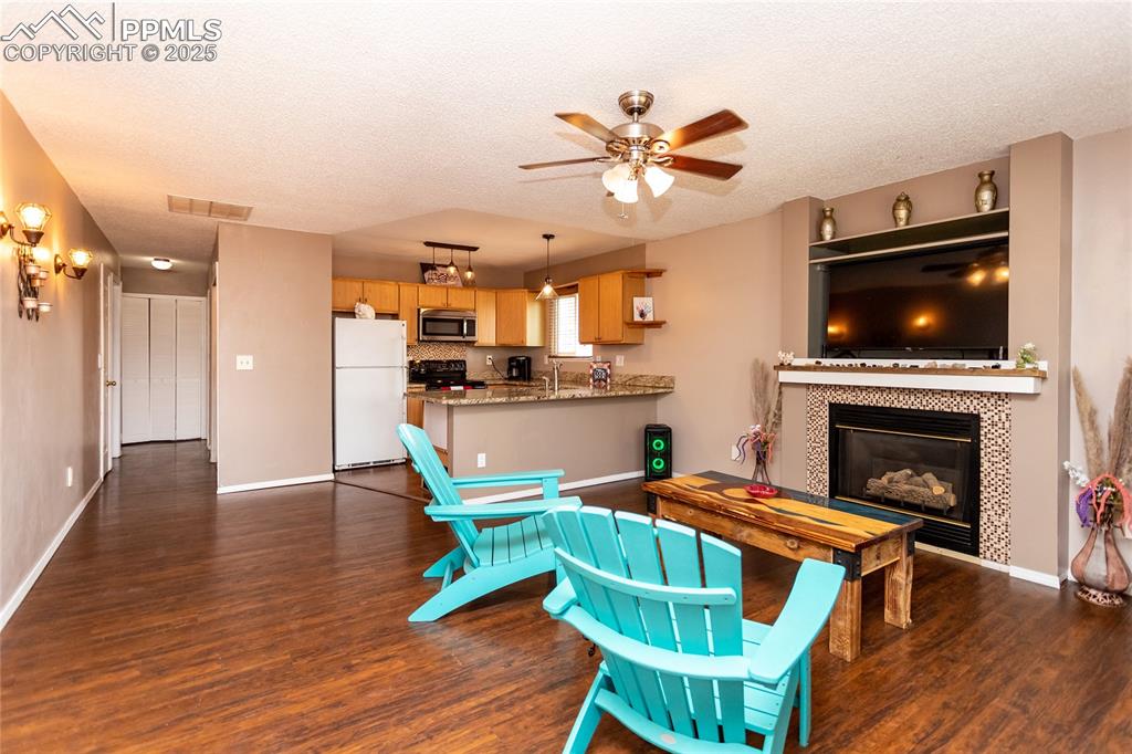 Image 42 of 50: Living room with dark wood-style floors, a ceiling fan, a textured ceiling,