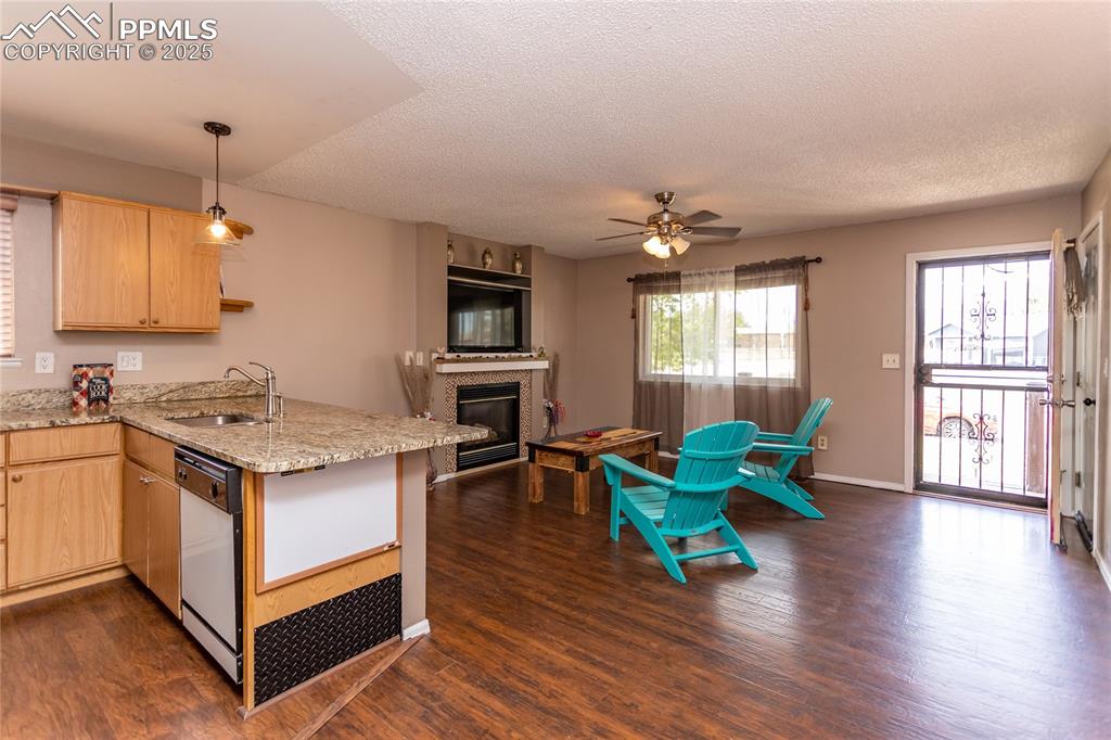 Image 45 of 50: Kitchen with light brown cabinets, white dishwasher, a sink, a peninsula, a