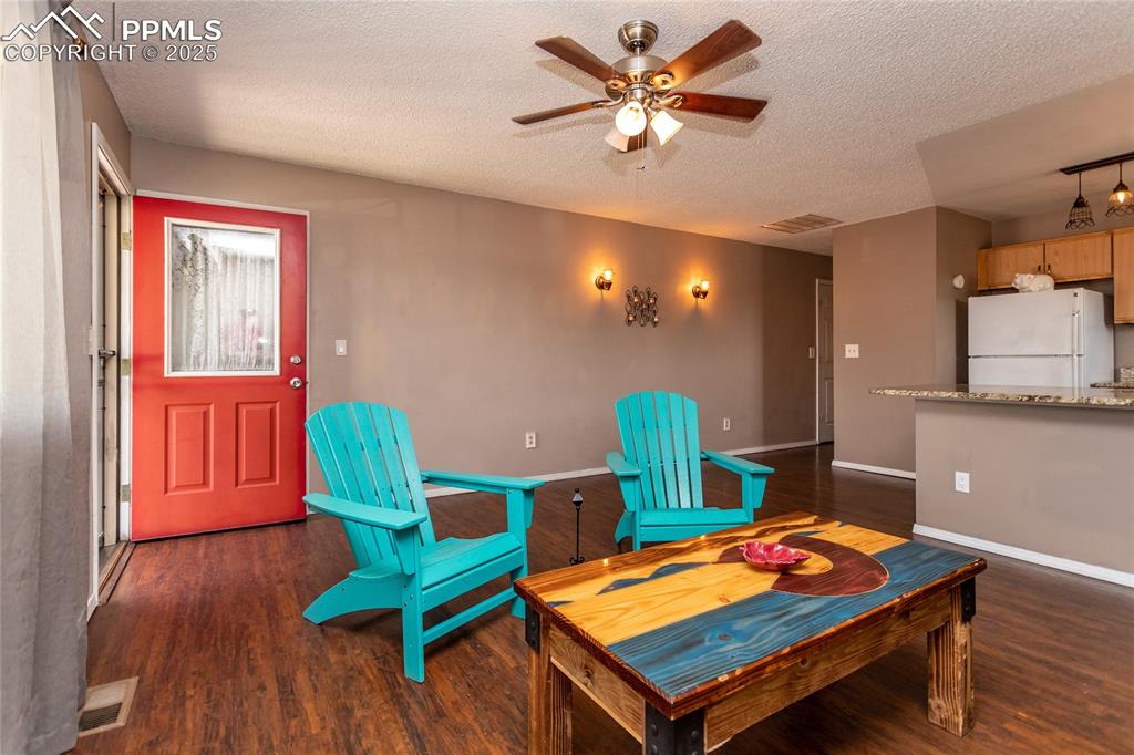 Image 47 of 50: Living area featuring wood finished floors, a ceiling fan, a textured ceili