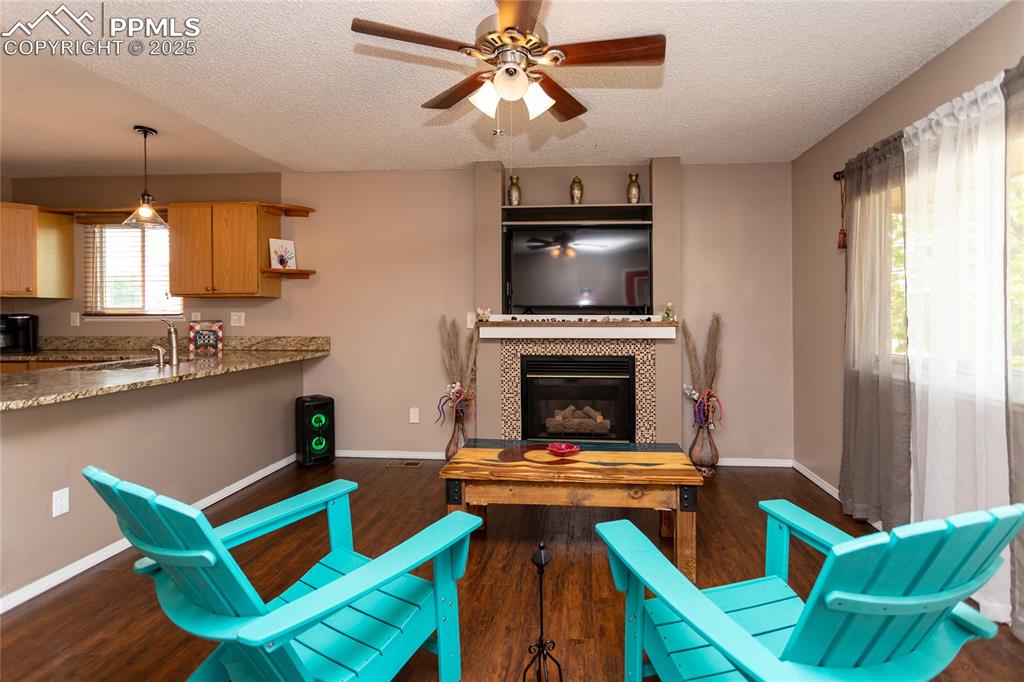 Image 49 of 50: Living room featuring a textured ceiling, ceiling fan, dark wood finished f