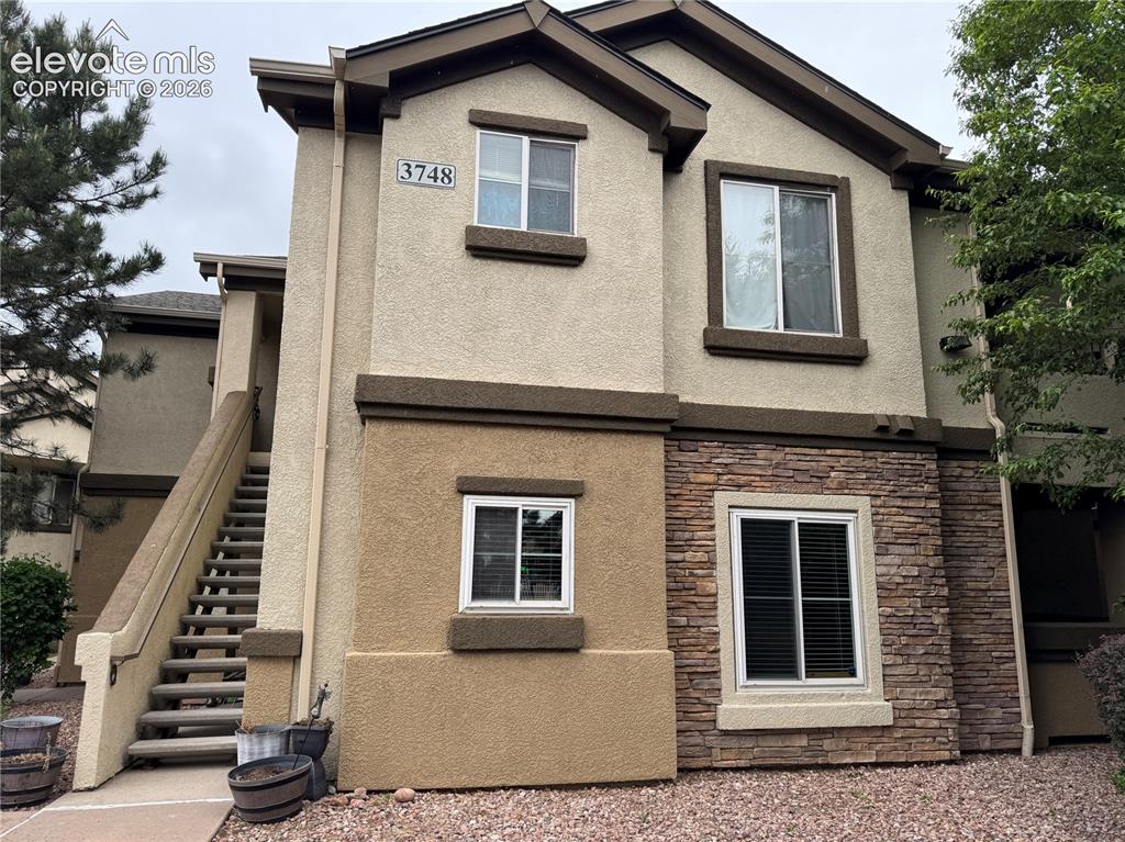 Image 1 of 32: Two-story stucco and stone-accented building with visible exterior stairs