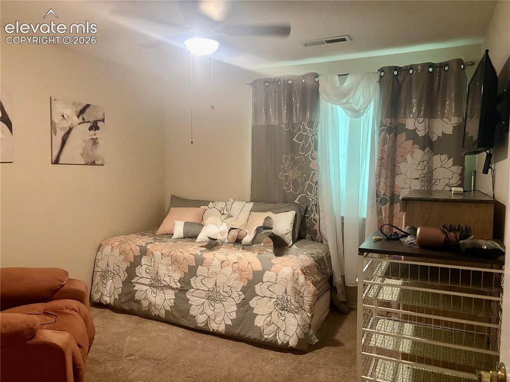 Image 23 of 32: Carpeted room featuring a ceiling fan with integrated lighting, a window wi